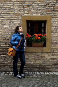 Full length of woman standing against brick wall