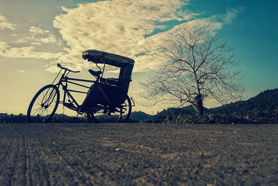Bare tree on field against sky during sunset