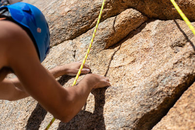 Close-up of shirtless man climbing rock