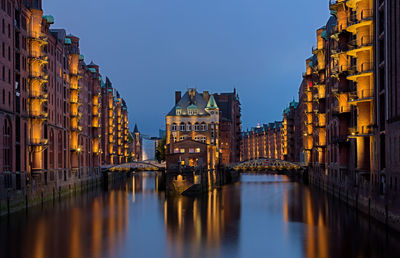 Canal amidst buildings in city at dusk