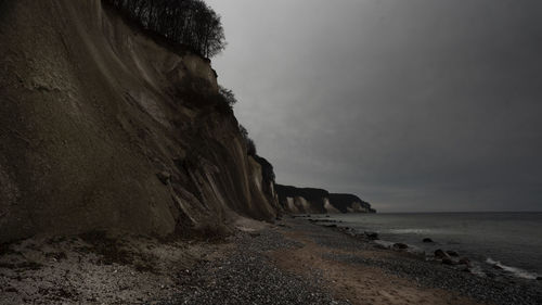 Rock formation on beach against sky