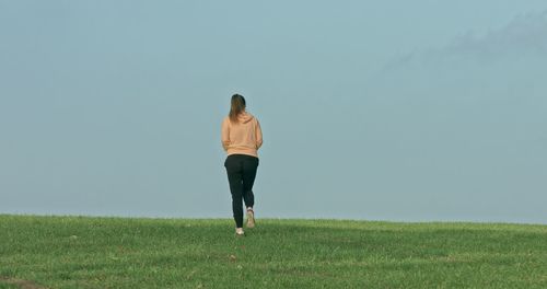 Rear view of woman running on field