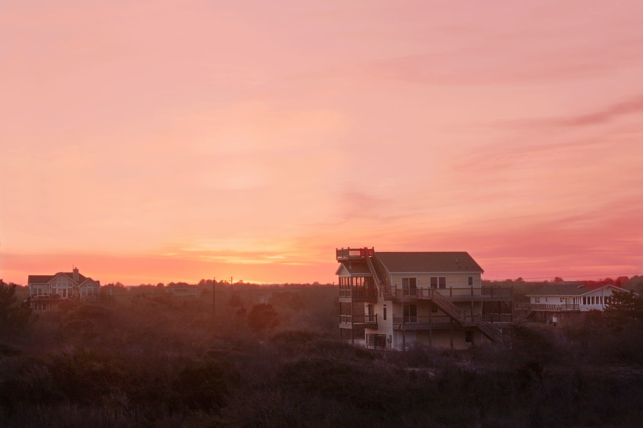 HOUSE ON FIELD AGAINST ORANGE SKY