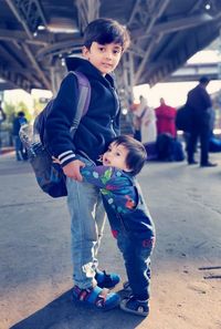 Full length portrait of siblings standing on railroad station platform