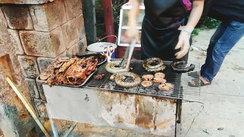 Midsection of woman preparing meat on barbeque grill