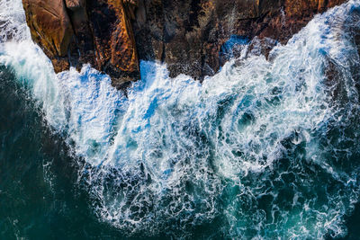 Aerial view of waves splashing on rocks