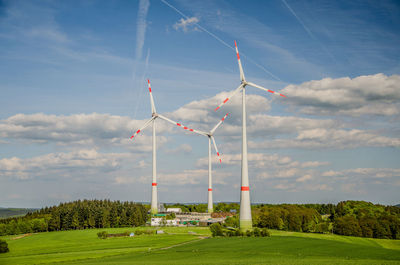 Scenic view of wind turbines on a field against sky