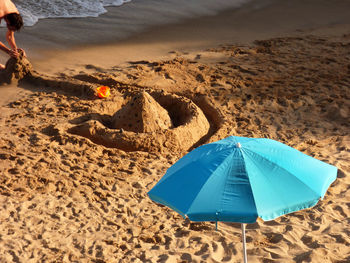 Open blue parasol on sand at beach