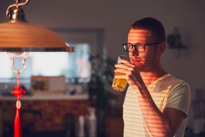 Young man having drink while standing at home
