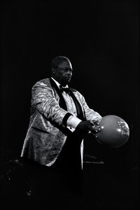 Young man looking away while standing against black background