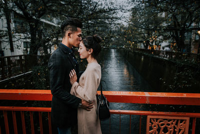 Young couple standing on railing by water