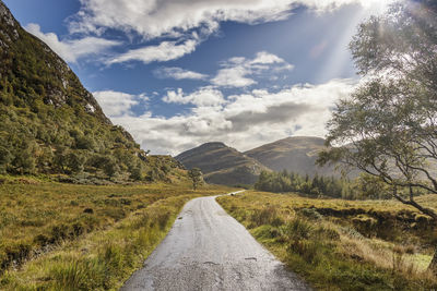 Road leading towards mountains against sky