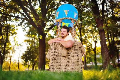 A large adult bearded man in the basket of a toy balloon.