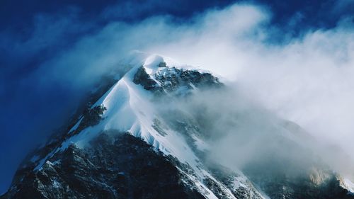 Scenic view of snowcapped mountains against cloudy sky