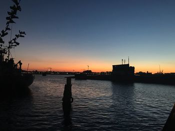 Silhouette harbor against clear sky during sunset