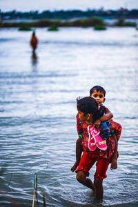 Rear view of mother with daughter in water