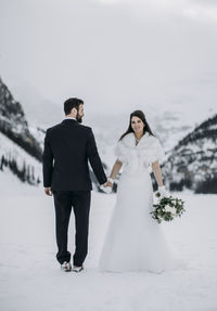 Bride smiles while holding hand of groom in winter on frozen lake
