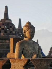 Statue against temple against sky