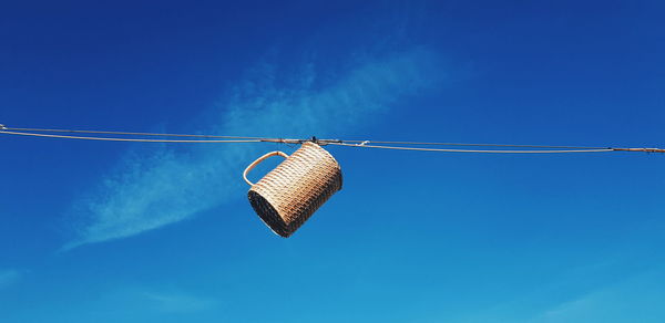 Low angle view of flags hanging against clear blue sky