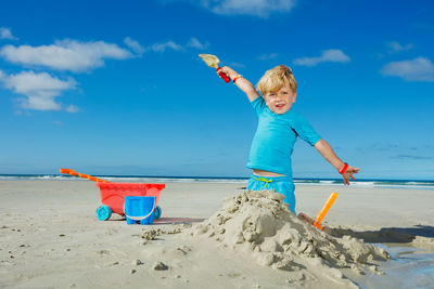 Rear view of man standing on sand at beach against sky