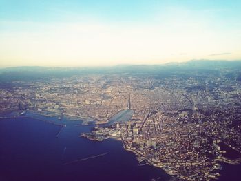 Aerial view of sea and cityscape against sky