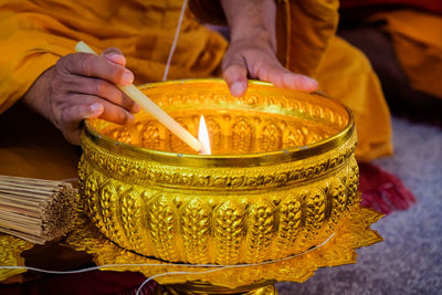 Midsection of man holding candles in temple