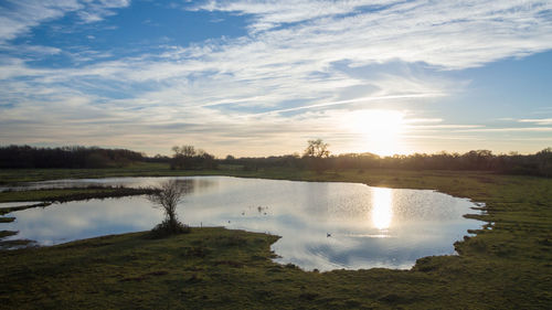 Scenic view of lake against sky at sunset