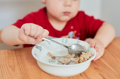 A boy is eating oatmeal for breakfast at the kitchen table