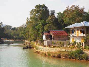 River by trees and building against sky