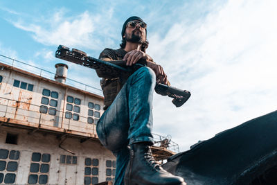 Low angle view of man photographing against sky