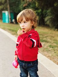 Cute boy eating lollipop while standing on road