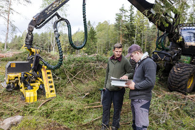 Men talking in front of forest machine