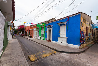 Road by buildings against sky