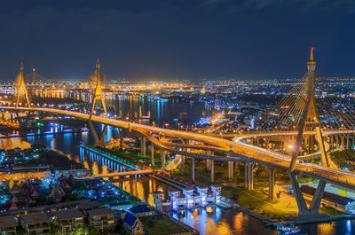 Illuminated bridge over river in city at night