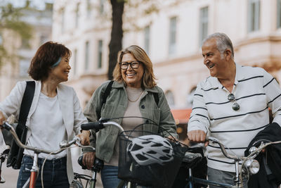 Happy male and female senior friends with bicycles on footpath