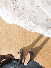 Low section of person standing at beach