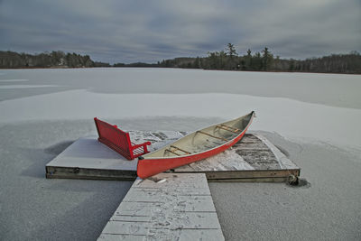 Red canoe and red bench in the snow