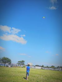 Full length of boy standing on field against sky