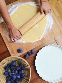 Cropped hands of person rolling dough on table