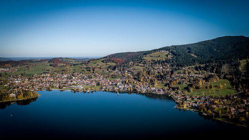 Scenic view of lake and mountains against clear blue sky