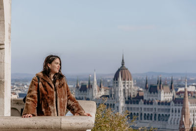 Portrait of girl standing on balcony overlooking city of budapest, hungary