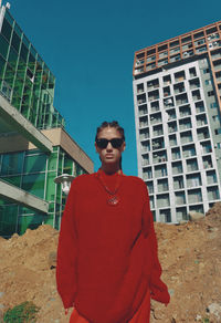 Portrait of young man wearing sunglasses standing against building