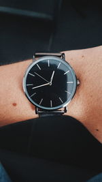 Close-up of hand against clock