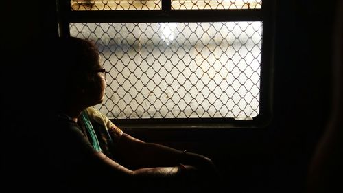 Woman looking through window while traveling in train