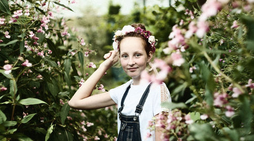 Portrait of young woman standing by flower tree