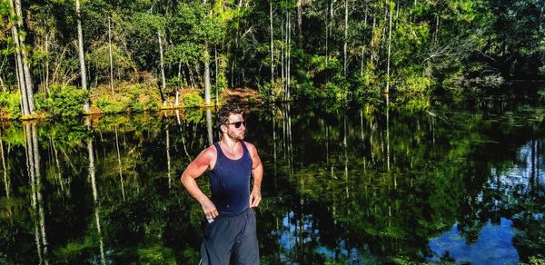 Young man standing by lake in forest