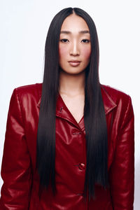 Portrait of young woman standing against white background