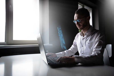 Side view of young man using laptop at home