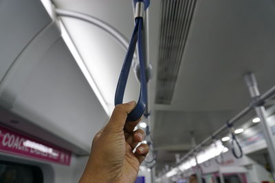 Cropped image of man holding handle in train