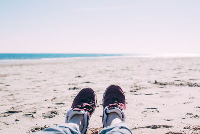 Low section of person on beach against sky